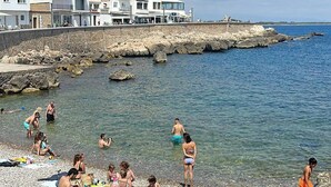 A coastal area with a rocky shoreline, clear water, and buildings in the background. - Casa del Pescadores - Four Bedroom House, Sleeps 8 (L'Escala)