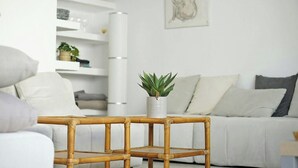 A modern living room with a white sofa, a bamboo coffee table with a plant, and a minimalist shelving unit against the wall. - Casa del Pescadores - Four Bedroom House, Sleeps 8 (L'Escala)