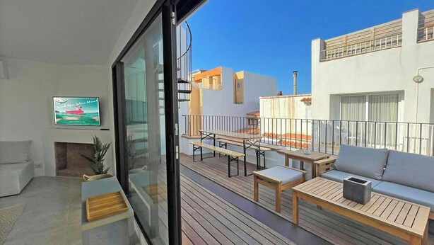 A modern living room with a large sliding glass door leading to an outdoor deck with wooden furniture and a sofa. - Casa del Pescadores - Four Bedroom House, Sleeps 8 (L'Escala)