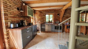 Une cuisine avec un mur en briques, des poutres en bois et une fenêtre.