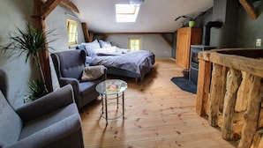Une chambre mansardée chaleureuse, avec un lit, une chaise, une petite table et un banc en bois.