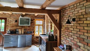Une cuisine rustique avec des poutres apparentes, un mur en briques et une fenêtre donnant sur un paysage verdoyant.