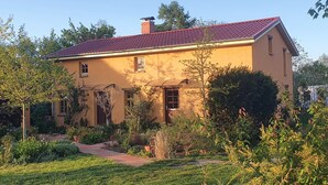 A two-story house with a red-tiled roof, surrounded by a well-maintained garden with various plants and a pathway leading to the entrance. - Boutique vacation apartment Westera on the sunny hill near the Baltic Sea! (Carinerland)