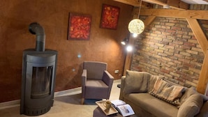 A cozy room with a fireplace, a sofa, and a chair. - Boutique vacation apartment Westera on the sunny hill near the Baltic Sea! (Carinerland)