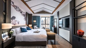 Habitación de hotel moderna con una cama grande, un escritorio con lámpara, una silla y vistas a la ciudad.