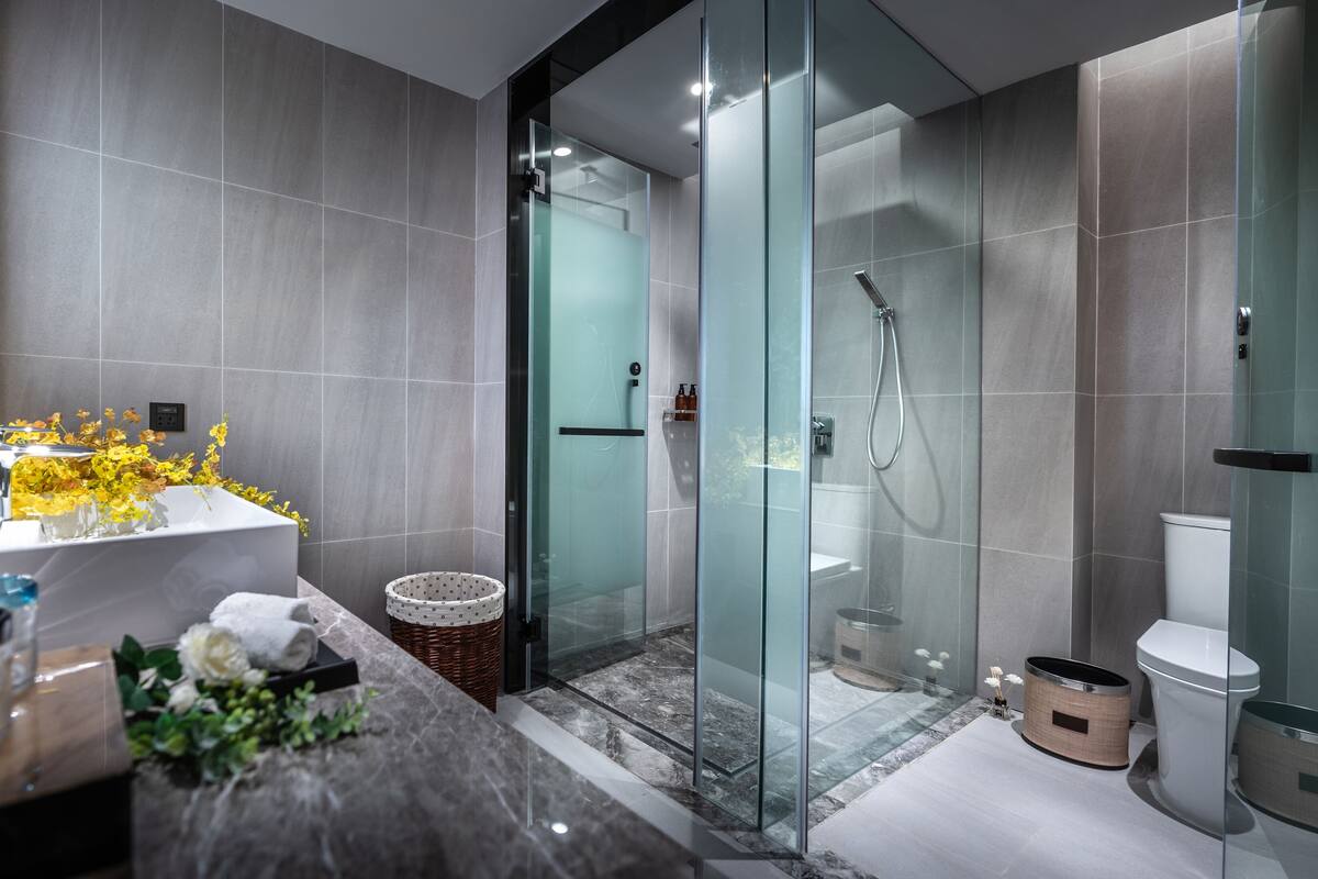 Un baño moderno con cabina de ducha de vidrio, lavamanos de mármol y un inodoro.