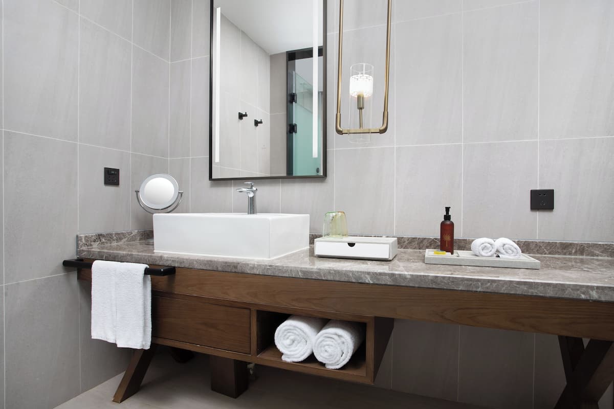 Un baño moderno con un espejo grande, un lavamanos, un perchero para toallas y un estante con toallas.