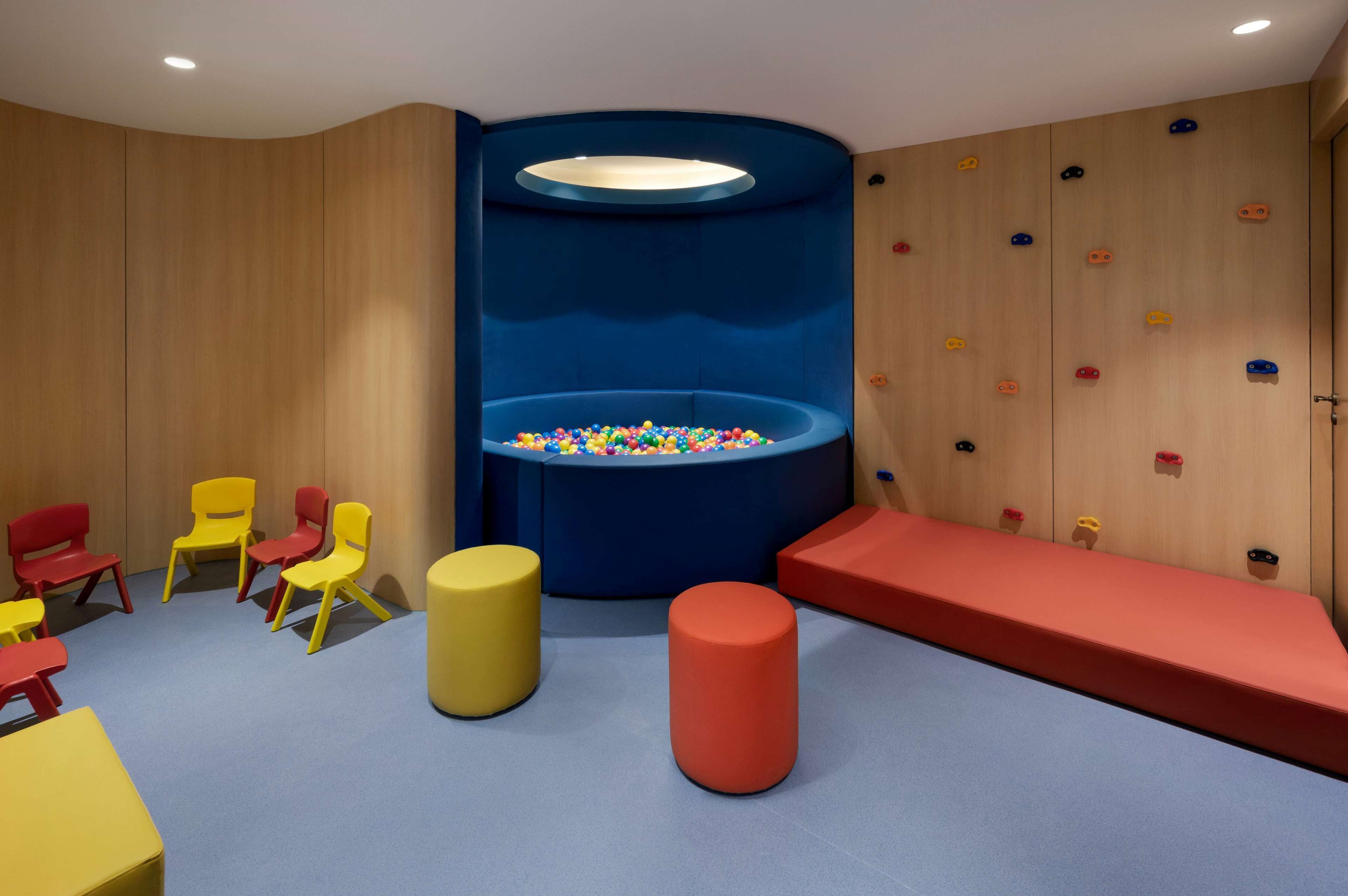 A play area with colorful chairs, a ball pit, and a climbing wall.