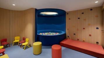 A play area with colorful chairs, a ball pit, and a climbing wall.