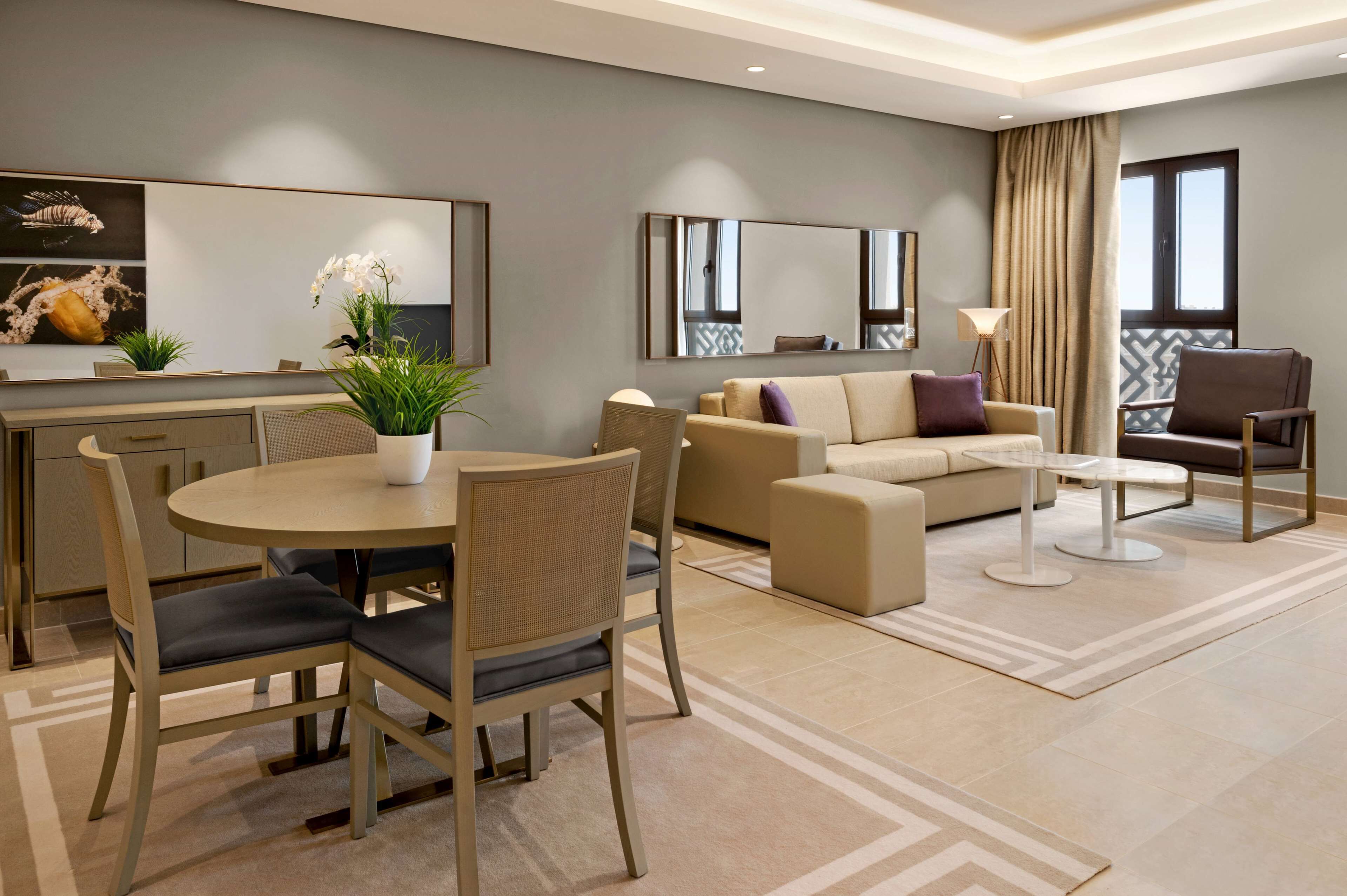 A modern living room with a dining area, a sofa set, a coffee table, and a large mirror.
