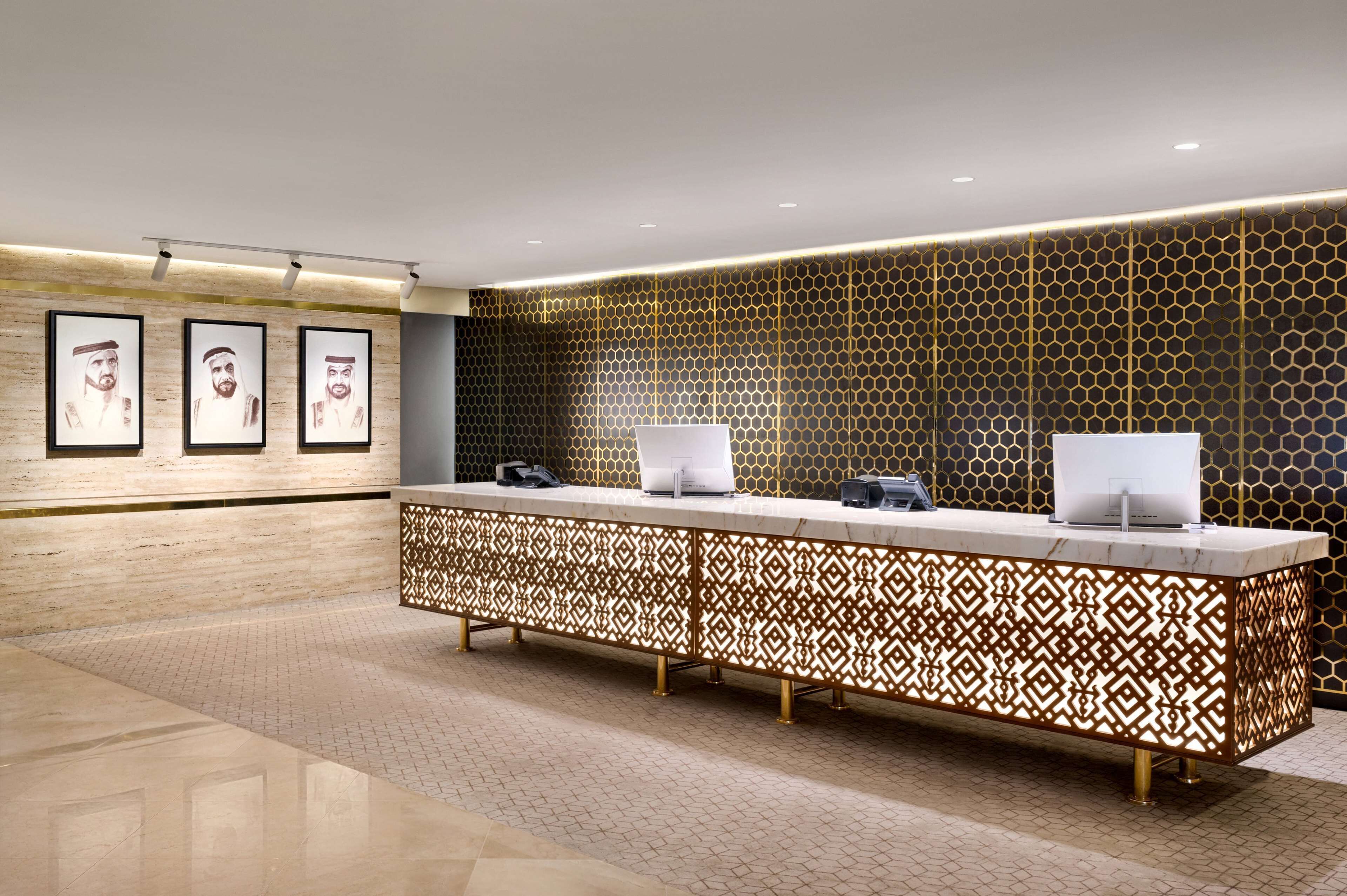 A reception area with a marble counter, framed portraits on the wall, and a honeycomb-patterned wall.