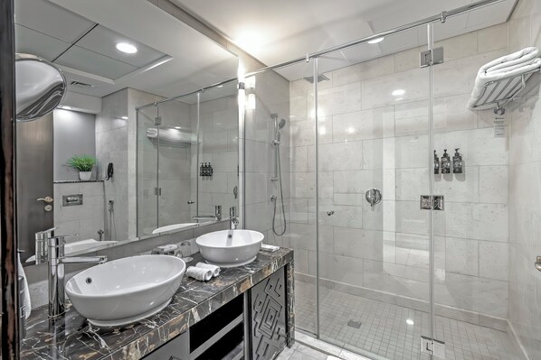 A modern bathroom with two sinks, a glass shower enclosure, and a marble vanity.