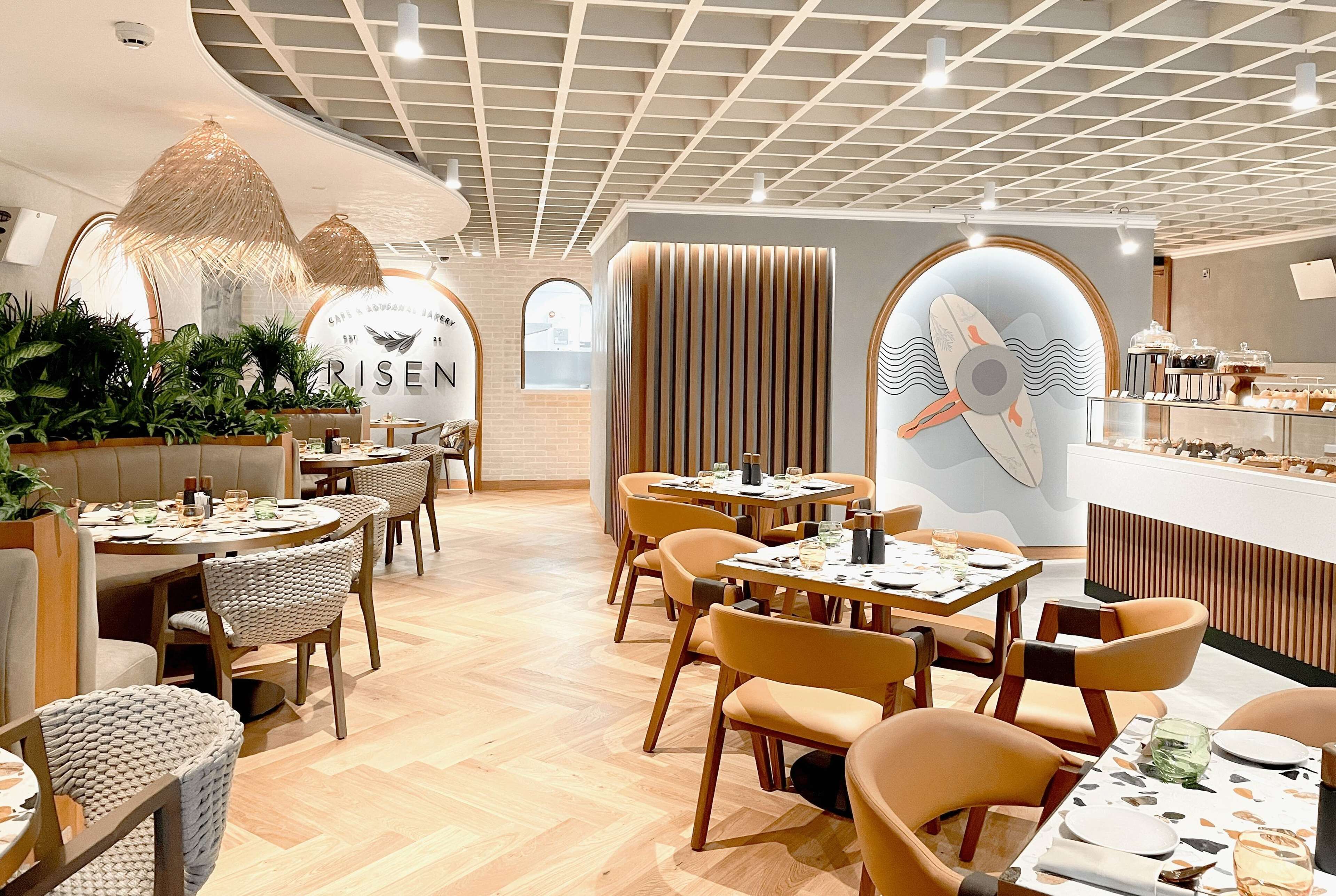 En modern restauranginteriör med runda bord, bekväma stolar och en central ö.