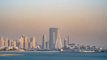 Un paisaje urbano costero con edificios altos, una torre destacada y un puerto deportivo.