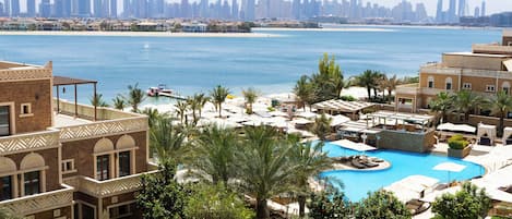 A resort with a swimming pool, palm trees, and a view of a city skyline.
