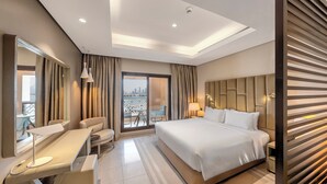 A modern hotel room with a large bed, a desk, a chair, and a balcony with a city view. - Wyndham Residences The Palm (Dubai)
