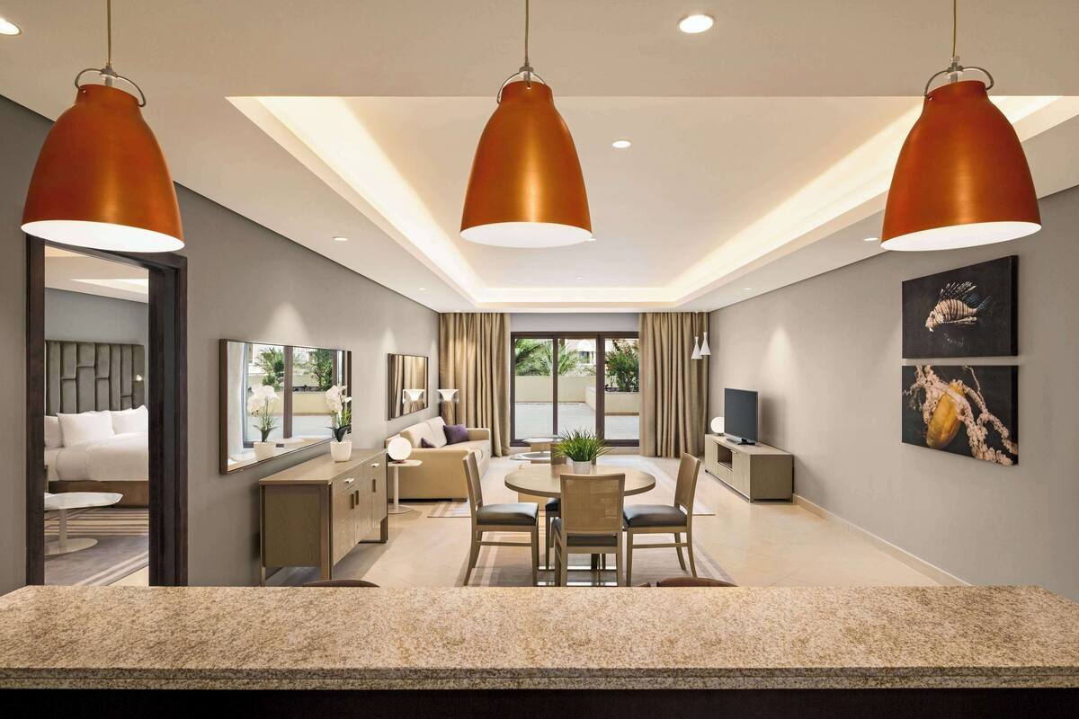 A modern hotel room with a dining area, a large mirror, and artwork on the walls.