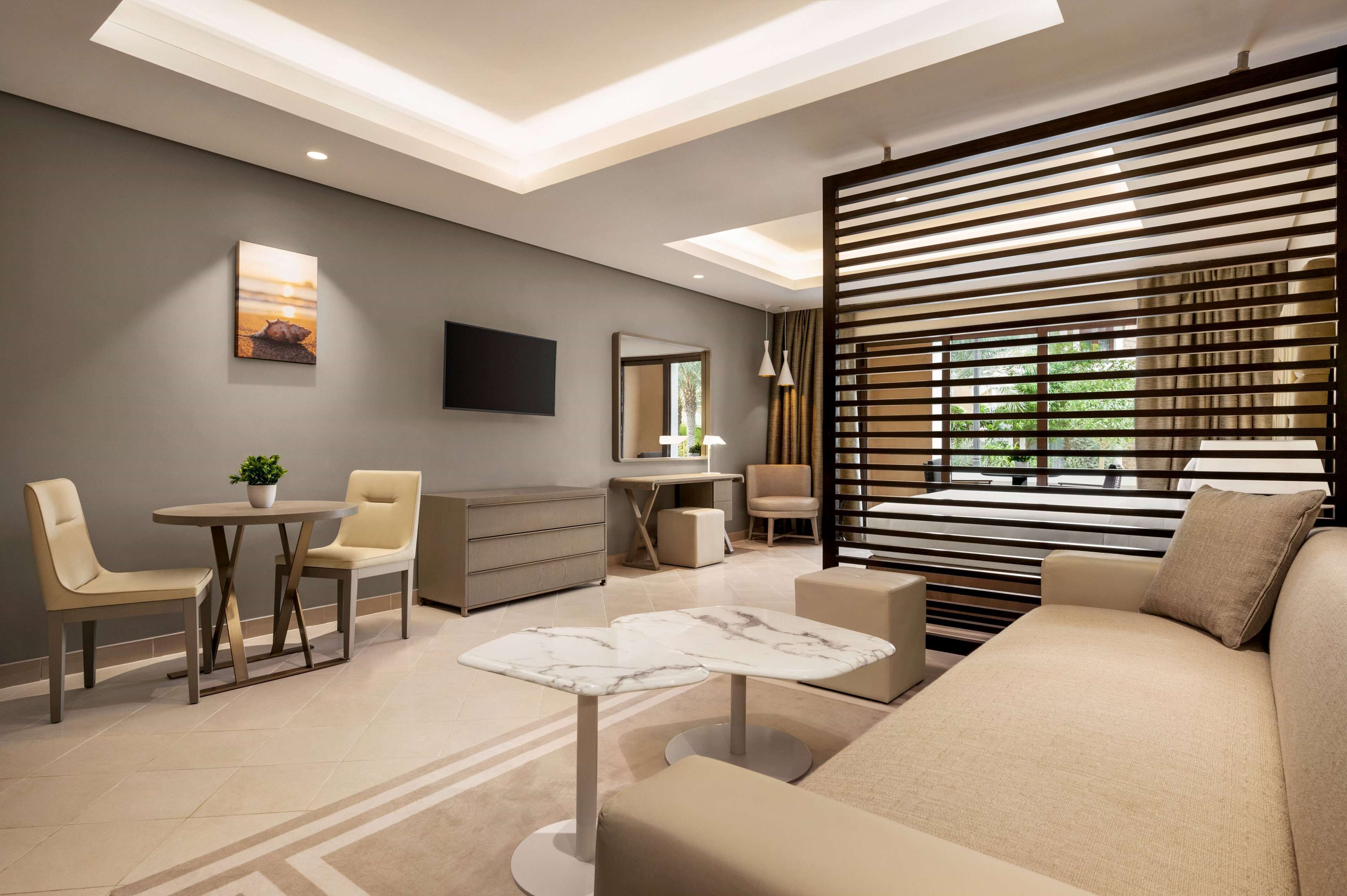 A modern living room with a sofa, two armchairs, a coffee table, and a TV mounted on the wall.