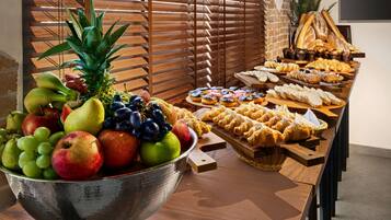 A buffet table with a variety of fruits and pastries.