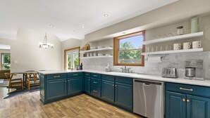 Une cuisine spacieuse avec des meubles de couleur turquoise, un grand îlot central et une fenêtre qui laisse entrer la lumière naturelle.