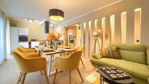 A modern living room with a dining area, featuring a green sofa, yellow chairs, and a coffee table with a game. - Villa MAGNIFICA with pool (Pinezići)