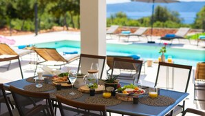 A dining table set with breakfast items and a view of a pool and lounge chairs. - Villa MAGNIFICA with pool (Pinezići)