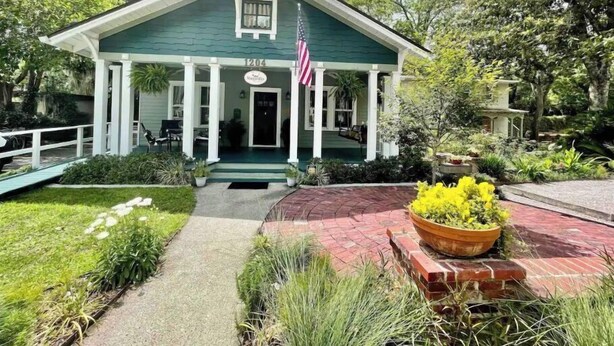 Un edificio verde con un portico, una bandiera americana e un cartello con su scritto "The Inn".