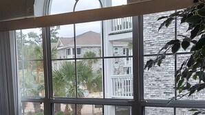 Ein Zimmer mit einem großen Bogenfenster, das Blick auf ein Steinhaus und einen gepflegten Garten bietet.