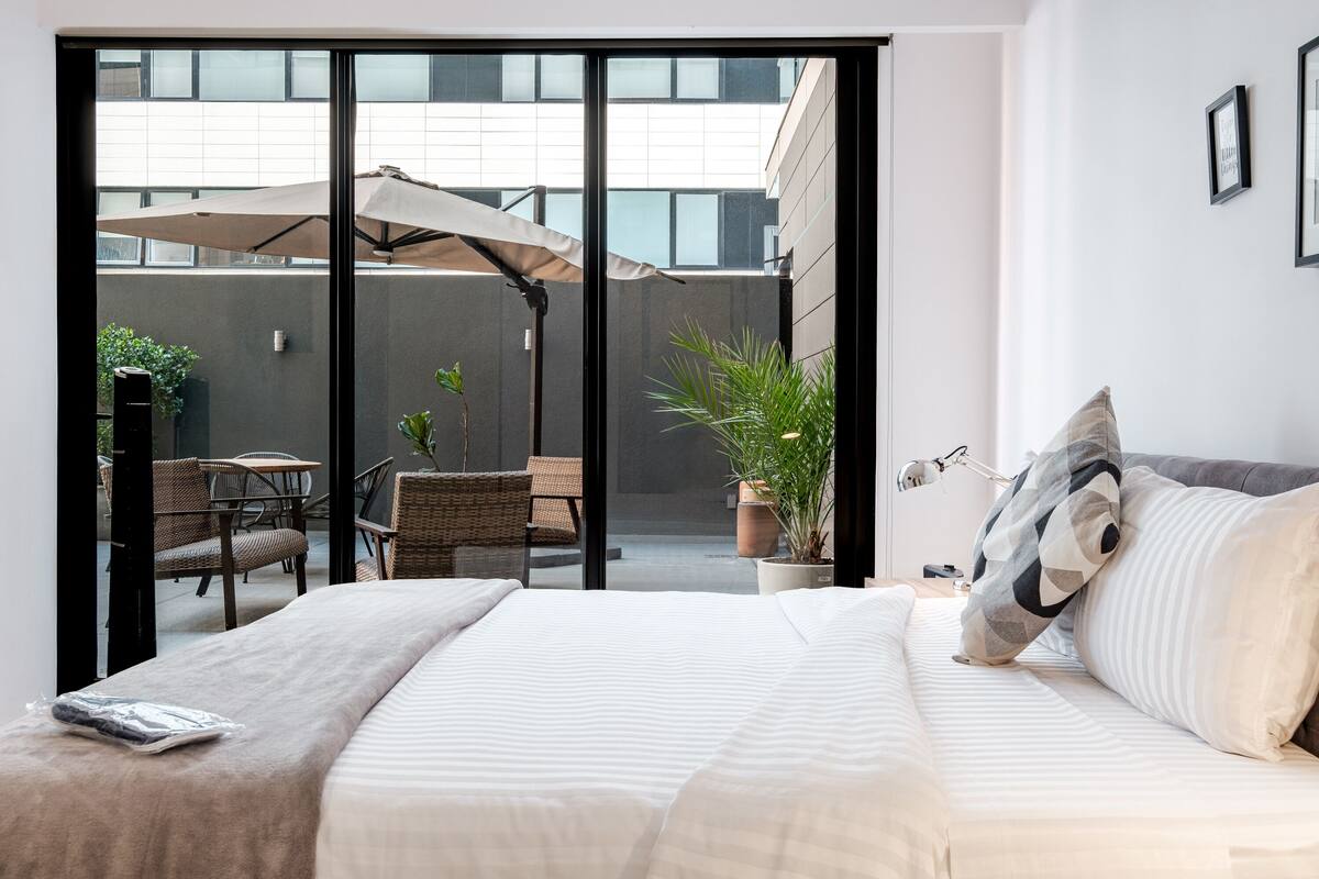 Ein modernes Hotelzimmer mit einem großen Bett, Blick auf den Außenbereich und einer Zimmerpflanze.