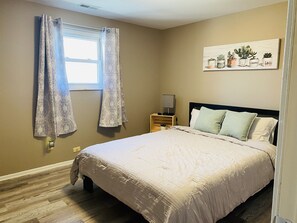 Cozy retreat with a bed, nightstand, and artwork of potted plants.