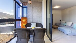Ein modernes Wohnzimmer mit Balkon, großen Fenstern und einer Pendelleuchte.