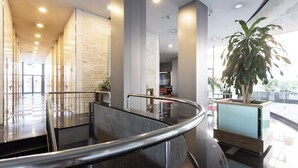 Ein modernes Interieur mit einer geschwungenen Treppe, einer Rezeption und einer großen Topfpflanze.