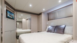 Un dormitorio moderno con una cama grande, un televisor montado en la pared y un vestidor.