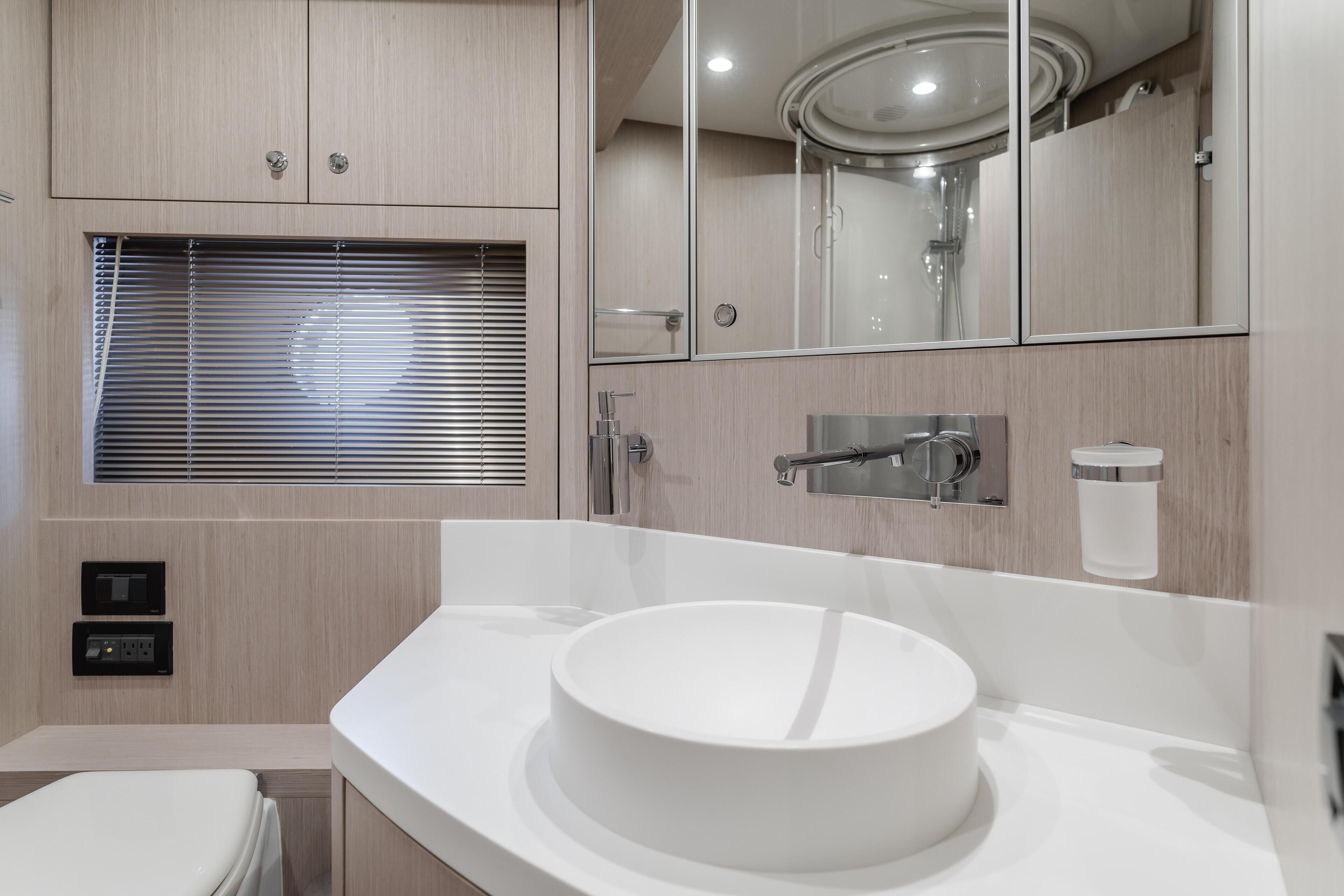 A modern bathroom with a round sink, a mirror, and a shower.