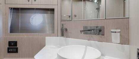 A modern bathroom with a round sink, a mirror, and a shower.