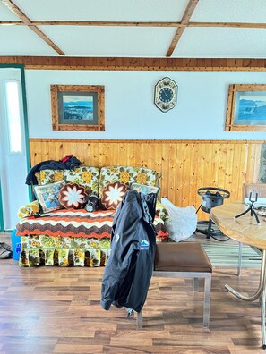 A room with a wooden headboard, a patterned sofa, a table with a tripod, and a framed clock on the wall. - Island-getaways cottage rental and cod fishing. We do island tours upon estuary (York Harbour)
