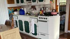 A kitchen with white cabinets, a stove, and a dining area with a table.