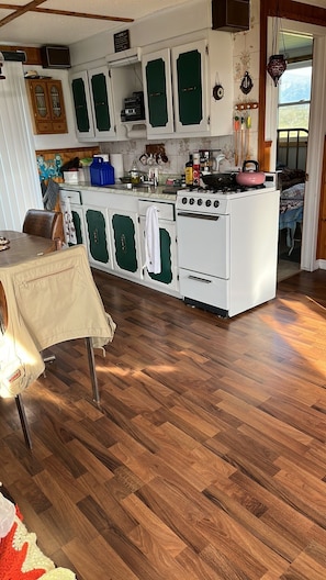 A kitchen with white cabinets, a stove, and a dining area with a table.