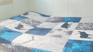 A bed with a quilt featuring animal silhouettes and a painting above it. - Island-getaways cottage rental and cod fishing. We do island tours upon estuary  (York Harbour)