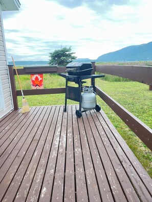 En træterrasse med grill og propanflaske.