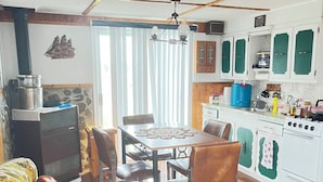 A cozy living room with a sofa, a dining table, and a kitchen area with cabinets and a stove. - Island-getaways cottage rental and cod fishing. We do island tours upon estuary  (York Harbour)