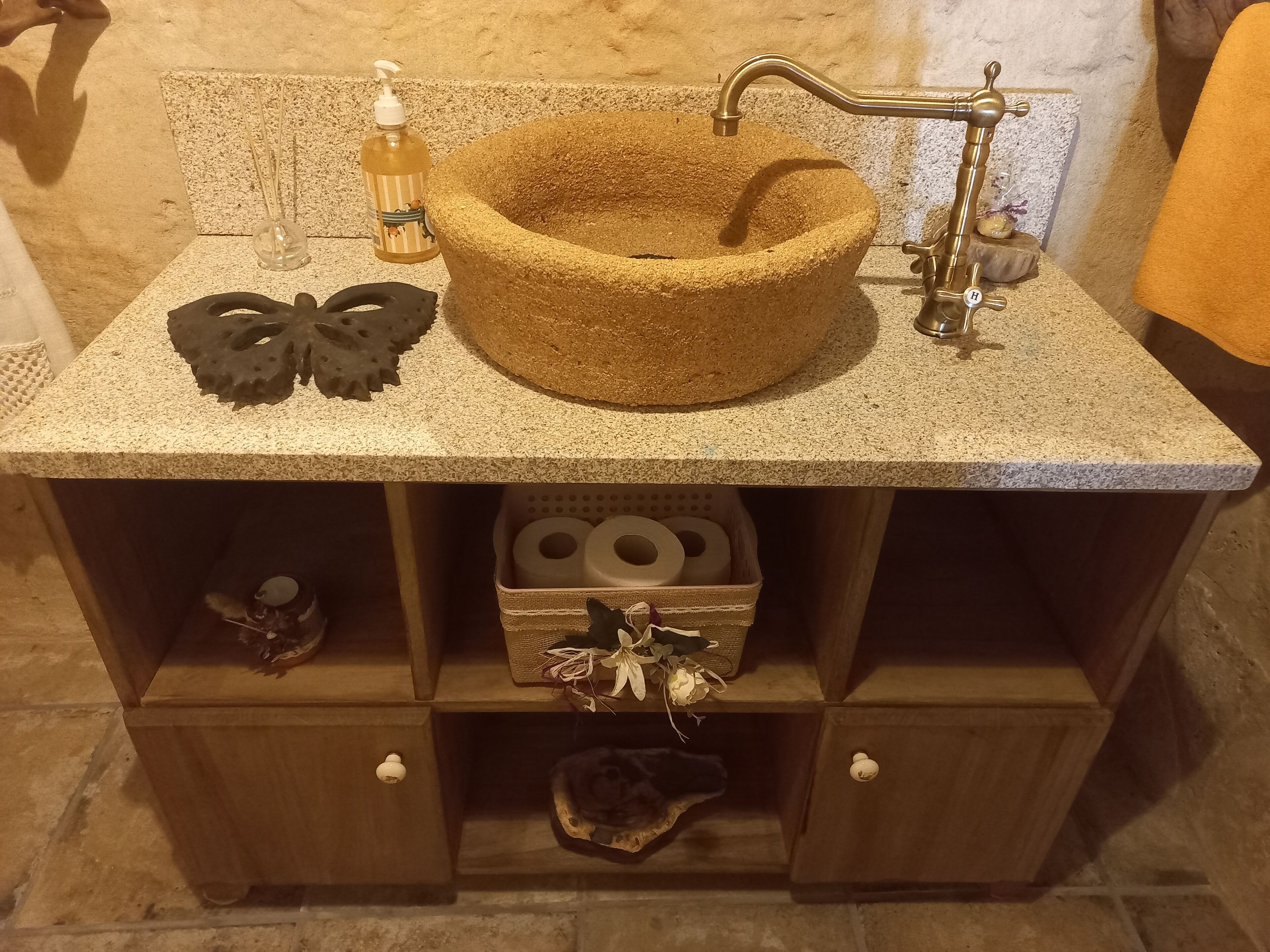 Un bany amb un rentamans de pedra, un dosificador de sabó i un objecte decoratiu al taulell.