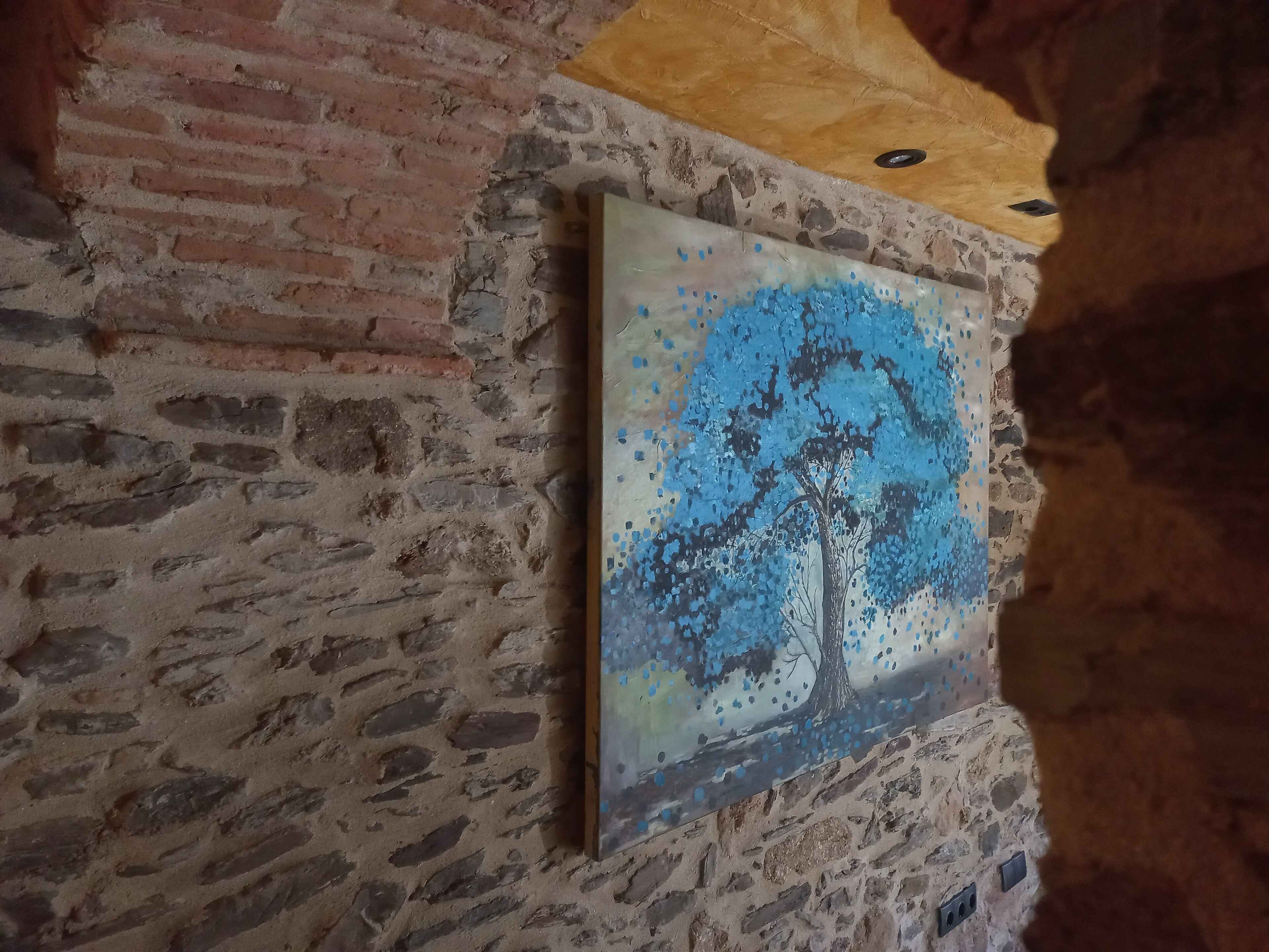 Een schilderij van een boom op een structuurwand.