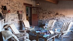 Une pièce rustique aux murs de pierre, meublée de meubles en bois, notamment des fauteuils et une table basse.