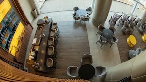 A spacious indoor area with multiple seating arrangements, including round tables and chairs, and a bar counter. - My Mabu (Foz do Iguaçu)