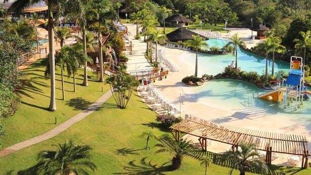 A resort with a large pool, lounge chairs, and palm trees. - My Mabu (Foz do Iguaçu)