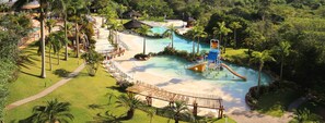 A resort with a large pool, lounge chairs, and palm trees.