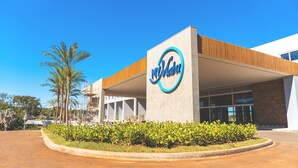 A modern hotel with a prominent sign, a covered entrance, and a landscaped area with greenery. - My Mabu (Foz do Iguaçu)