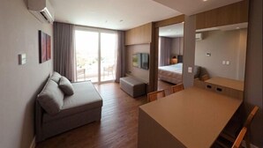 A modern hotel room with a sofa, a small table, a bed, and a large mirror. - My Mabu (Foz do Iguaçu)