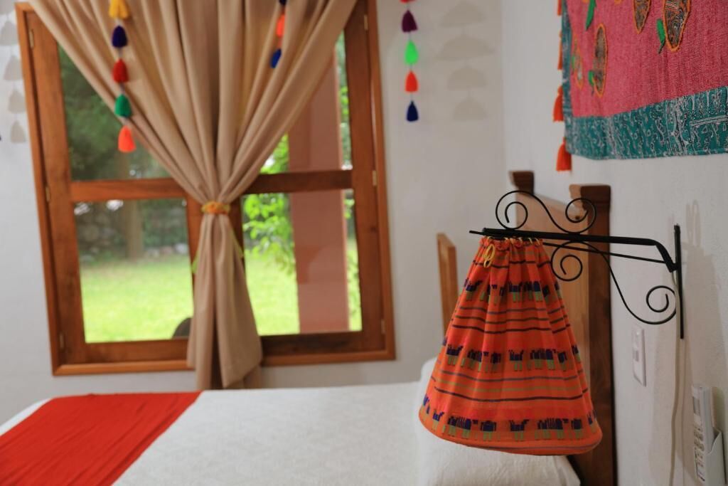 Een slaapkamer met een bed, een raam met gordijnen, en een wandrek met kleding.